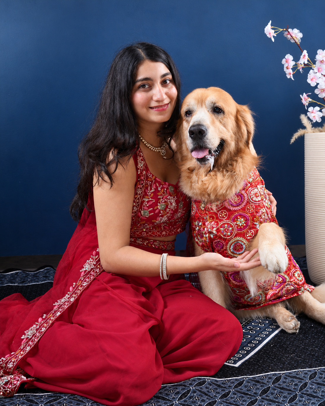 Woman in a red outfit sitting with a Golden Retriever wearing the Royal Embroidered dog kurta